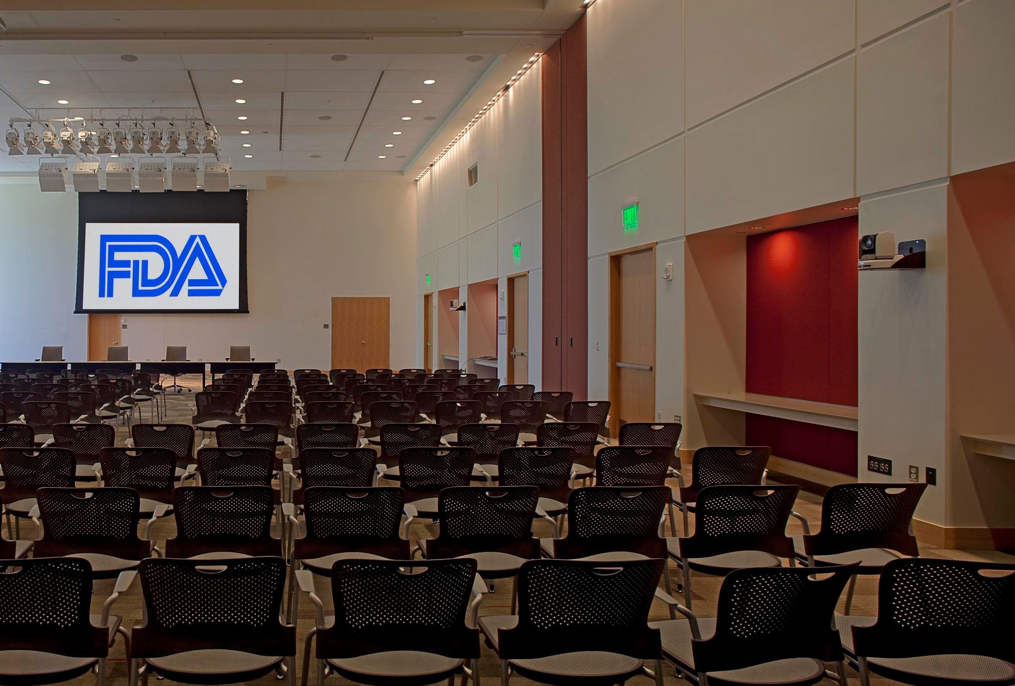 photo shows an empty conference room and a large screen with the FDA logo on it